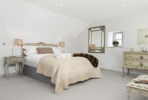 a bedroom with a bed with a blanket and a mirror at Mole End Cottage in North Cerney