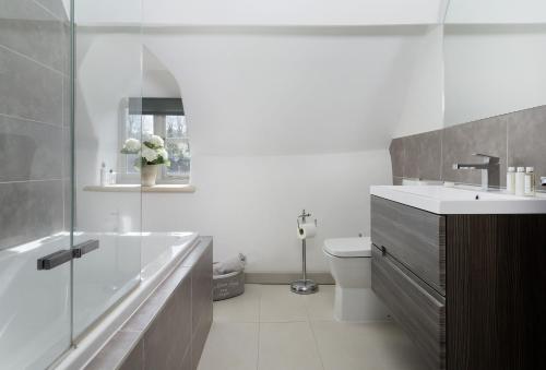 La salle de bains est pourvue d'une baignoire, d'un lavabo et de toilettes. dans l'établissement Mole End Cottage, à North Cerney