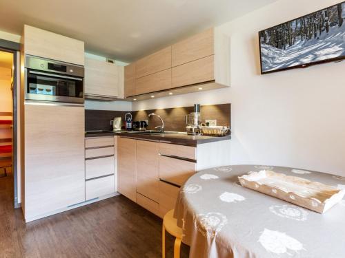 une cuisine avec des placards en bois et une table dans l'établissement Studio cosy au pied des pistes avec terrasse, garage et WIFI - La Clusaz - FR-1-437-66, à La Clusaz