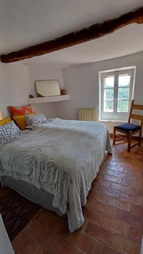 a bedroom with a bed and a chair and a window at Maison Porte Heureuse in Roussillon