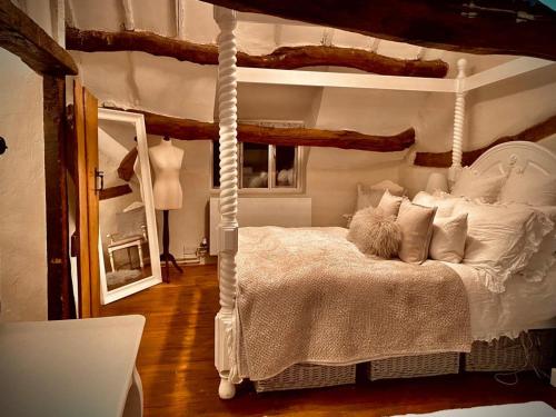 a bedroom with a canopy bed and a mirror at Mansfield Cottage in Kilsby