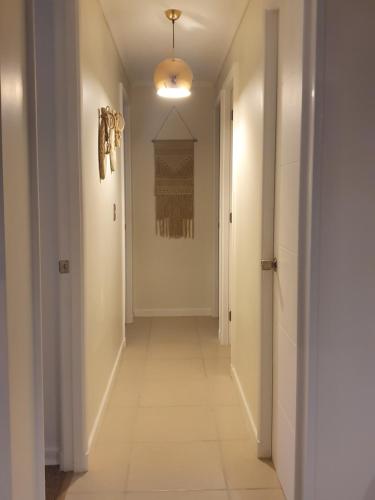a hallway with white walls and a white floor and a hallwayngth at Hermoso Departamento in El Tabo