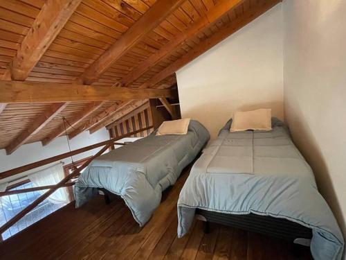 2 camas en una habitación con techos de madera en El Farolito House Bariloche en San Carlos de Bariloche