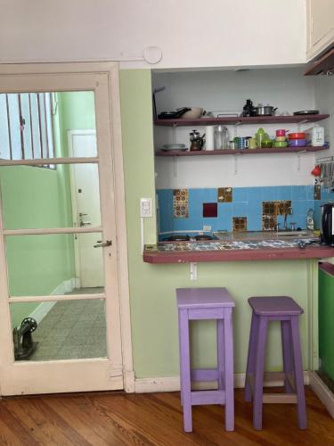 una cocina con taburetes púrpura junto a un mostrador en Apartment Corazón de San Telmo en Buenos Aires