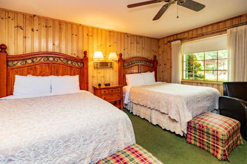 two beds in a bedroom with wood paneling at Azalea Garden Inn in Blowing Rock