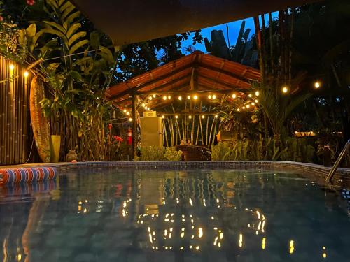 a swimming pool in front of a house with lights at Cabinas D’Val in Uvita