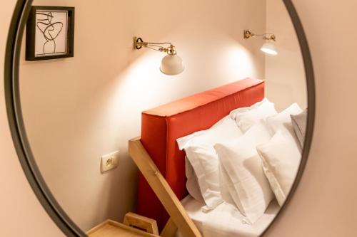 a mirror in a room with a bed with white pillows at Bella Vasilica Luxury Apartments in Parga
