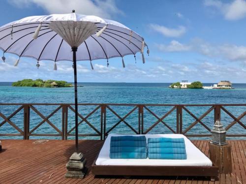 two chairs and an umbrella on a deck with the ocean at Isla Única- Islas del Rosario in Isla Grande