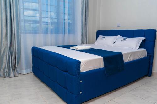 een blauw bed in een kamer met een raam bij Pearl Suites and Hospitality in Bungoma