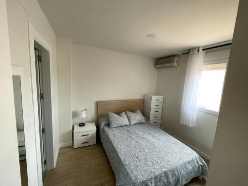 a bedroom with a bed and a dresser and a window at Ático con vistas a Sierra Nevada in Armilla