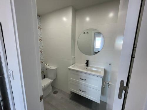 een badkamer met een wastafel, een toilet en een spiegel bij Ático con vistas a Sierra Nevada in Armilla