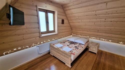 a small bedroom with a bed in a wooden room at Pokoje Pod Modrzewiami in Ciche