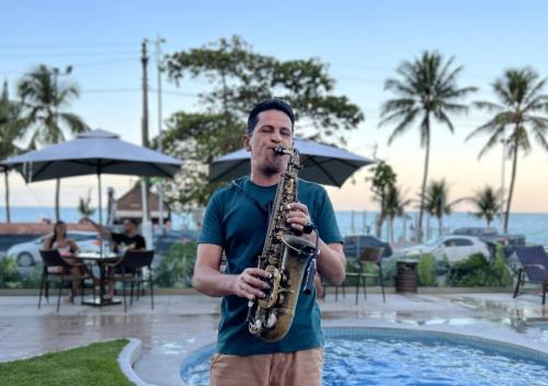 a man playing a saxophone in front of a pool at Hotel Ponta Verde Maceió in Maceió