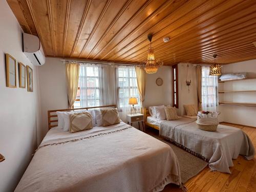een slaapkamer met 2 bedden en een houten plafond bij Hanole Guest House in Ayvalık