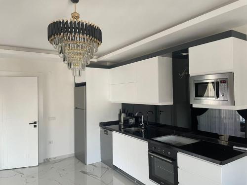 a kitchen with white cabinets and a chandelier at Fully furnished 1+1 apartment in luxury complex Heaven Hills in Mahmutlar