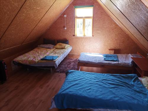 セイニにあるDomek z balaのベッド2台と窓が備わる屋根裏部屋です。