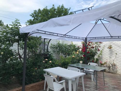 einen weißen Regenschirm auf einer Terrasse mit Tischen und Stühlen in der Unterkunft Vilari Odessa in Odessa