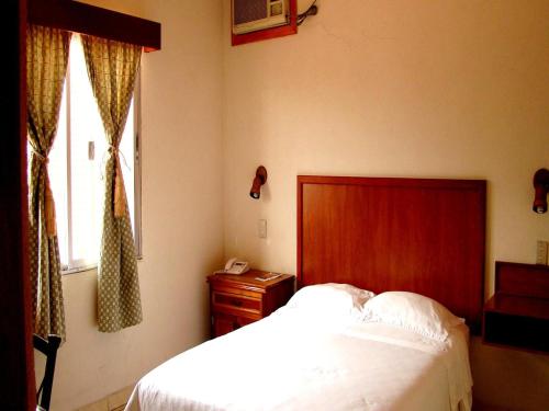 a bedroom with a bed with a wooden headboard and a window at Apart-Hotel River View in Tegucigalpa