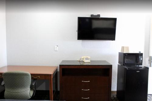 a hotel room with a desk and a tv and a chair at Economy Inn in Ada