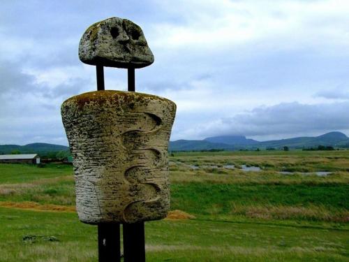 a stone statue with a hat on top of a field at Ari Villa Révfülöp in Révfülöp