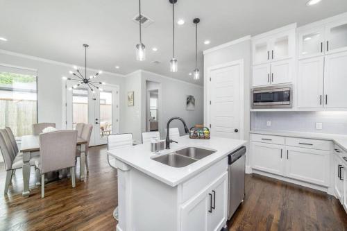 a white kitchen with a sink and a table at Glam Paradise 5BRs Downtown Dallas in Dallas
