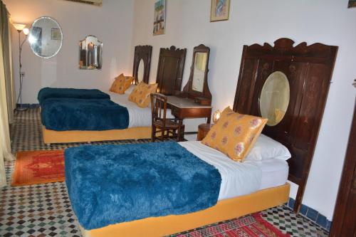 a bedroom with two beds and a table and a mirror at Dar Al Batoul in Fès