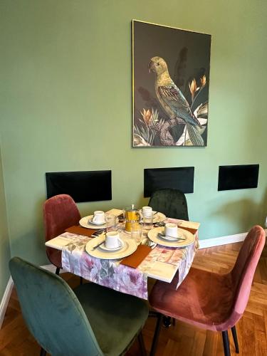 einen Esstisch mit Stühlen und ein Vogelbild an der Wand in der Unterkunft A casa di Bruna in Gorizia