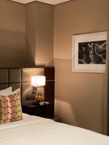a bedroom with a bed and a lamp and a picture at The Plaza Garden Hotel and Residences in Baguio