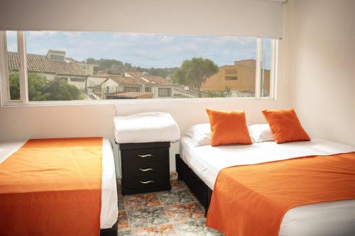 two beds in a room with a window at Hotel BogoSuba 127 in Bogotá