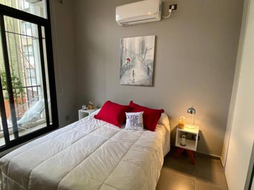 1 dormitorio con 1 cama blanca grande con almohadas rojas en Precioso departamento 2 ambientes Julian A. y Castillo en Buenos Aires