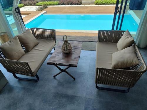 two chairs and a couch and a table next to a pool at Ocean Nadi 4 Bedrooms Beachfront Villa PD in Port Dickson