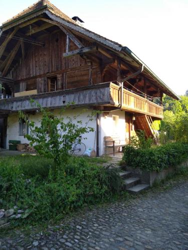 a large wooden house with a balcony on the side at Dachstockzimmer in altem Stöckli in Steffisburg