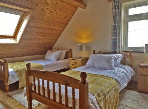 two beds in a room with two windows at Lands End Cottage - Connemara in Aughrus More