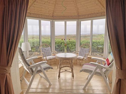 a dining room with a table and chairs and windows at Lands End Cottage - Connemara in Aughrus More