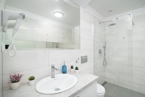 a white bathroom with a sink and a toilet at Róża Bałtyku - Apartamenty i Pokoje A in Dębki