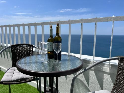 two bottles of wine sitting on a table on a balcony at Axenic Retreat - Panoramic Ocean View, Private Terrace, Sleeps 4, Ensuite Bathroom, New Redesign in Sesimbra