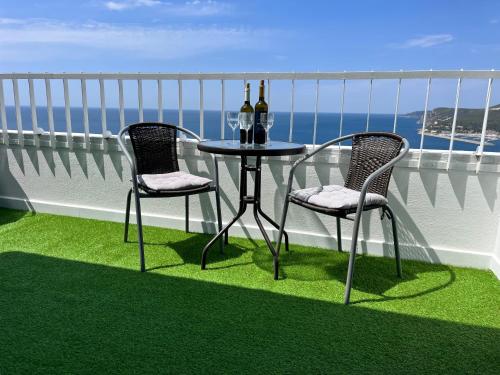 a table with two chairs and two bottles of wine on a balcony at Axenic Retreat - Panoramic Ocean View, Private Terrace, Sleeps 4, Ensuite Bathroom, New Redesign in Sesimbra