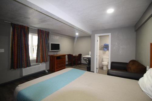 een slaapkamer met een bed, een bureau en een televisie bij Starlite Motel in San Bernardino