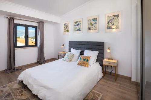 ein Schlafzimmer mit einem großen weißen Bett und einem Fenster in der Unterkunft Casa Relax à Olhos Albufeira in Albufeira