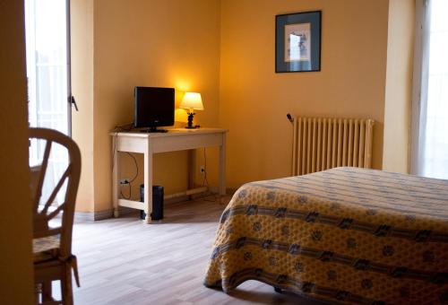a bedroom with a bed and a desk with a television at Hotel Rural Loizu in Burguete