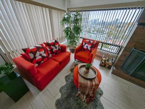 a living room with a red couch and two chairs at Casa Cacho in Tijuana