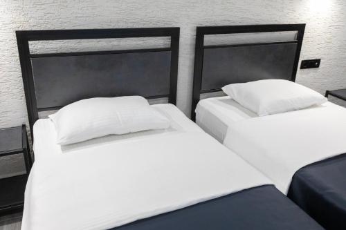 two beds in a room with white sheets and pillows at Hotel West Way in Kutaisi