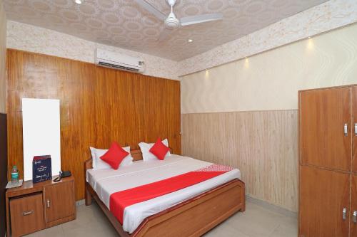 1 dormitorio con 1 cama grande con almohadas rojas en OYO 13234 Hotel Mahak, en Bijnaur