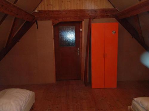 Zimmer im Dachgeschoss mit orangefarbener Tür und einem Bett in der Unterkunft Dachstockzimmer in altem Stöckli in Steffisburg