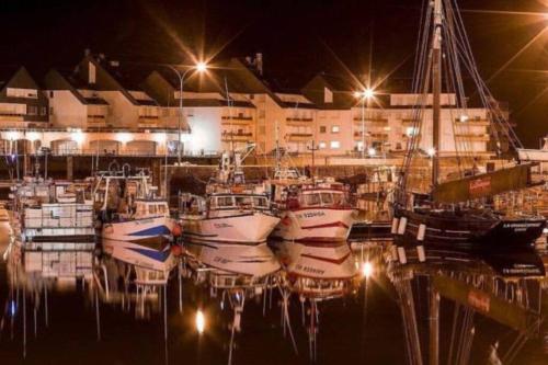 a group of boats docked in a marina at night at Appartement sur le port. in Grandcamp-Maisy