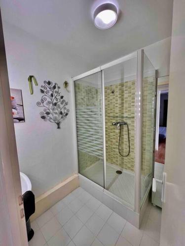 une salle de bain avec une douche avec une porte vitrée dans l'établissement Appartement sur le port., à Grandcamp-Maisy