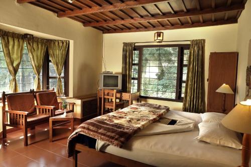 sypialnia z łóżkiem, krzesłem i telewizorem w obiekcie Olive Brook w mieście Munnar