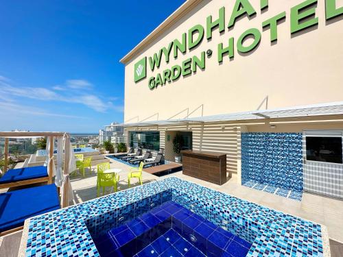 a hotel with a swimming pool in front of a building at Wyndham Garden Barranquilla in Barranquilla