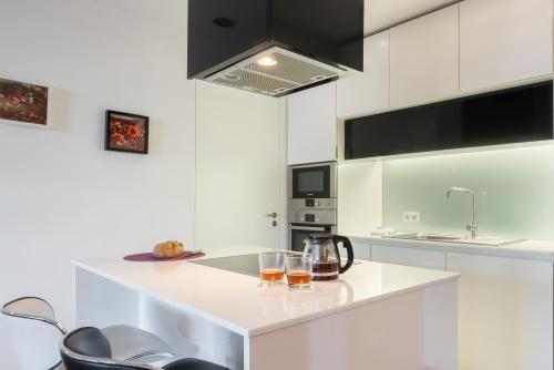 a white kitchen with two glasses on a counter at Apartamento Qian Caves Gaia 2BR AC Free Parking in Vila Nova de Gaia