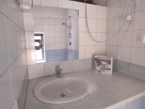 uma casa de banho branca com um lavatório e um espelho em Via Re Federico 13 em Ribera